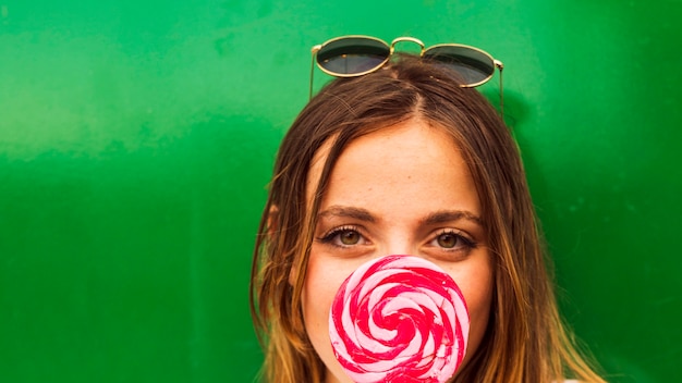 Free Photo woman's face holding red and pink lollipop in front of her mouth