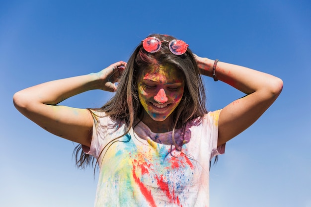 Woman's face with holi colors standing against blue sky