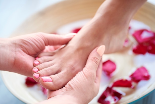 Woman's feet in bowl with water and petal