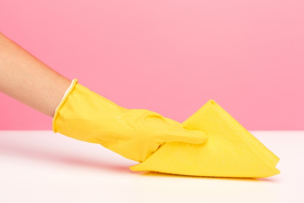 Free photo the woman's hand cleaning on a pink wall. cleaning or housekeeping concept