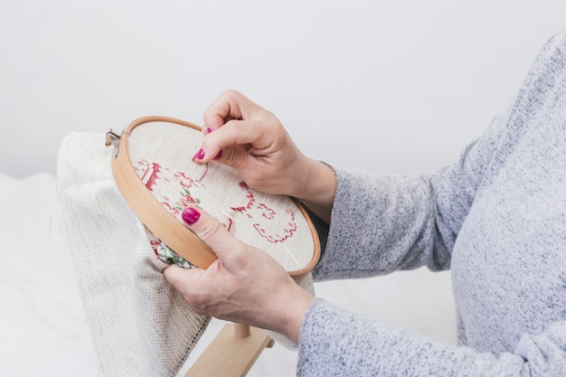 Free photo woman's hand cross stitching pattern on a hoop against white background