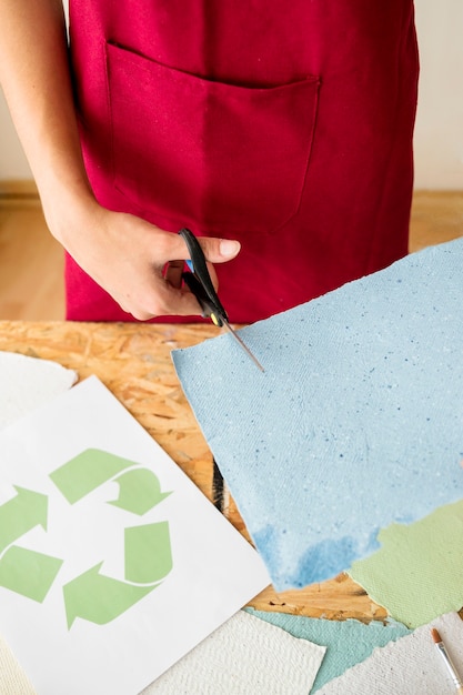 Woman's hand cutting blue paper with scissors