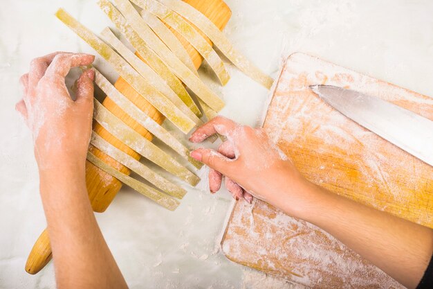 Woman's hand drying pasta on rolling pin