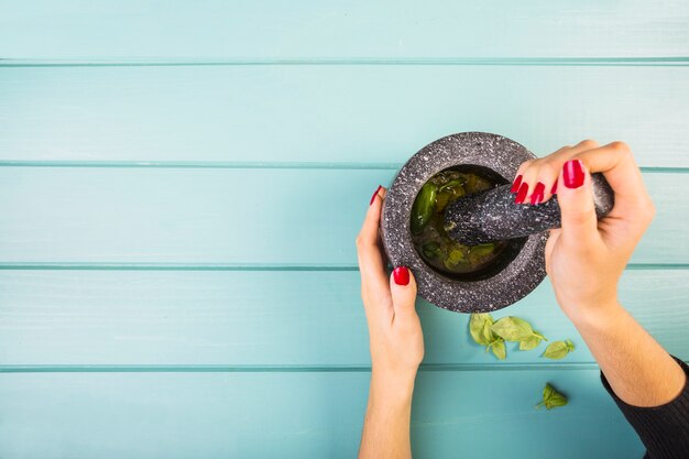 Woman's hand grinding herbs by mortar and pestle