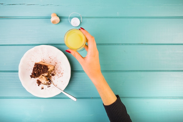 Free photo woman's hand holding drink with pastry on table