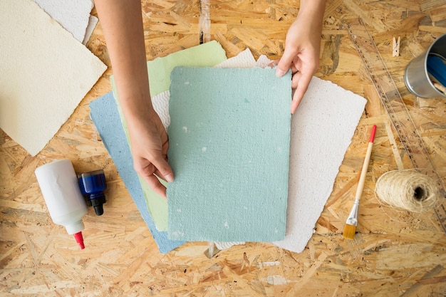 Free photo woman's hand holding handmade paper over wooden desk