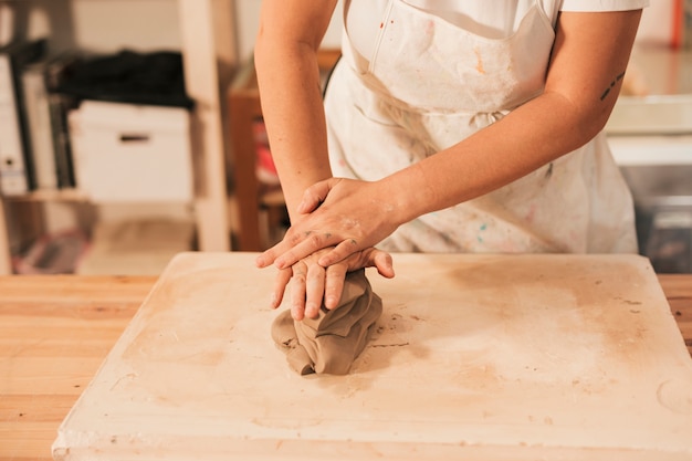 Free photo woman's hand kneading a clay on the table