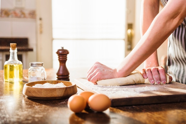 Free photo woman's hand kneading dough with ingredients on wooden table