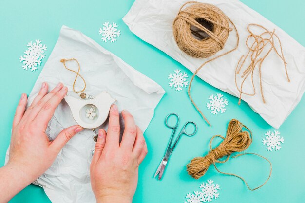 Woman's hand making the bird wall hanging on turquoise backdrop