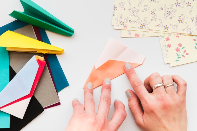 Free photo woman's hand making paper airplane on white backdrop