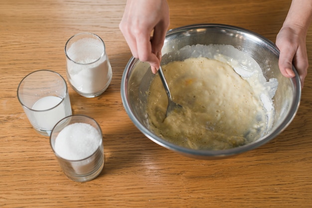 Woman's hand mixing the baking dough in the stainless bowl