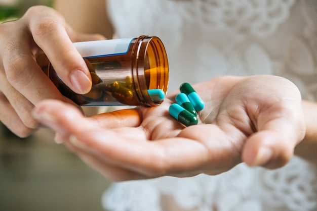 Woman's hand pours the medicine pills out of the bottle