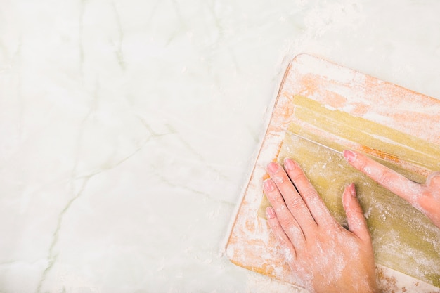 Free photo woman's hand preparing pasta on chopping board