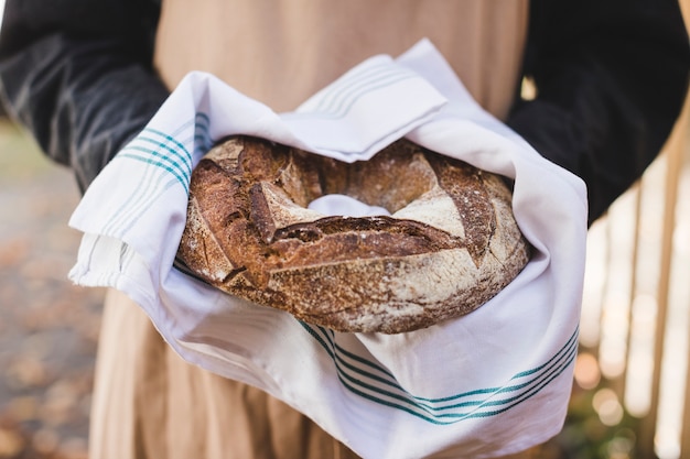 Woman's hand showing rustic bagel bread in white napkin