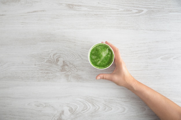 Woman's hand takes away paper glass with prepared japanese organic premium matcha tea latte.