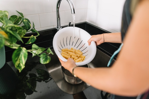 Free Photo woman's hand washing rigatoni pasta in the white colander