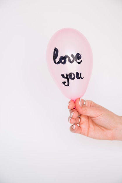 Free photo woman's hand with balloon with love you inscription