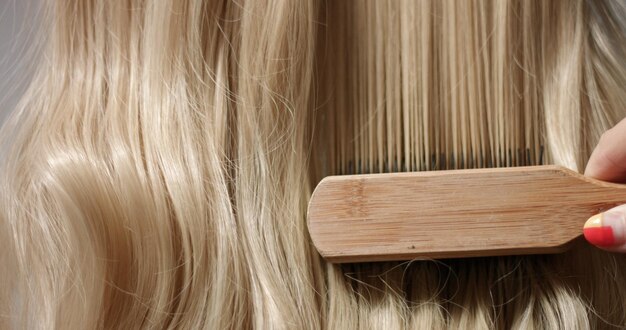 A woman's hand with bright manicure running through long wavy blond hair