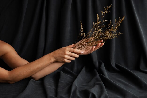 Woman's hands holding plant with dark curtain