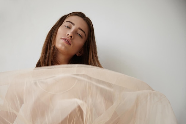 Free photo woman's portrait in a white room with soft light from window