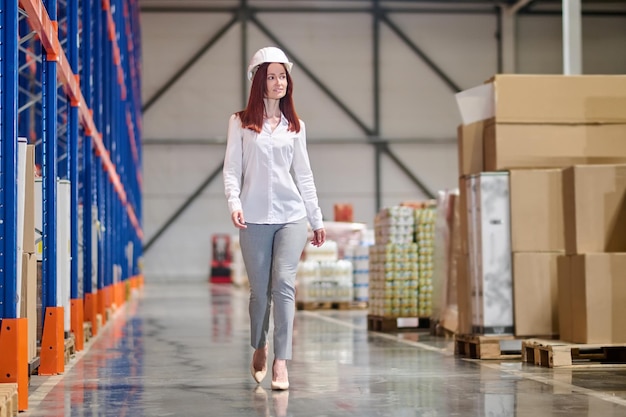 Free photo woman in safety helmet walking on warehouse