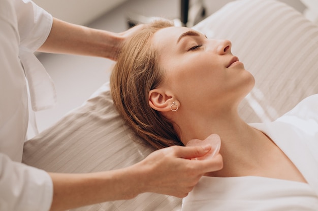 Woman in salon making beauty treatment with gua sha stone