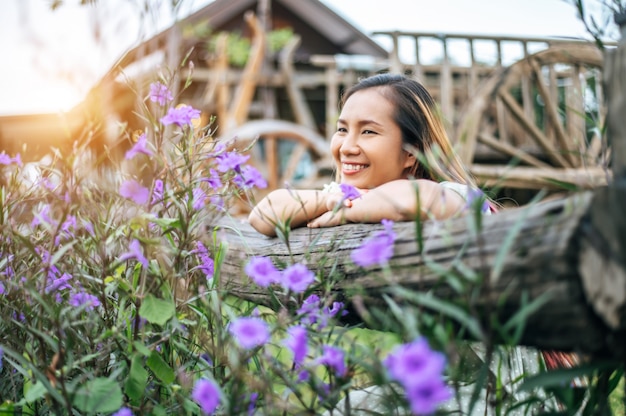 woman sat happily in the flower garden and laid her hands and towards the wooden fence