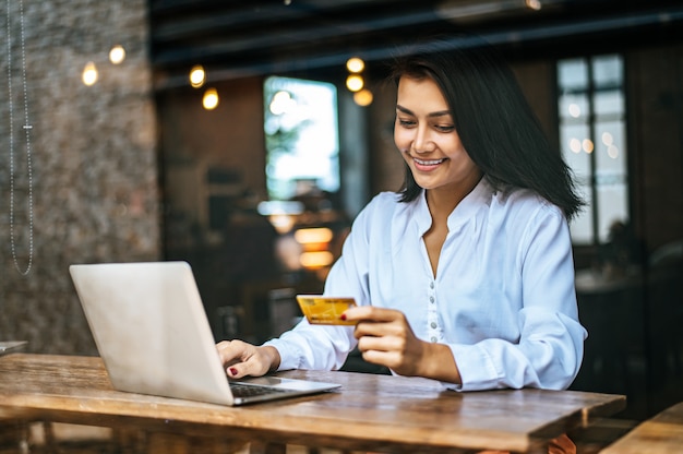 woman sat with a laptop and paid with a credit card in a cafe