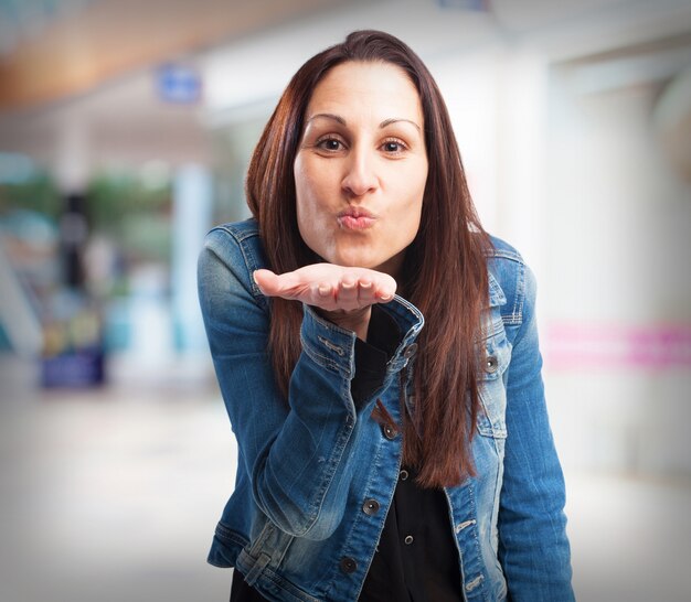 Woman sending a kiss with one hand in her mouth