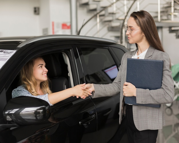 Free photo woman shaking hands with car dealer