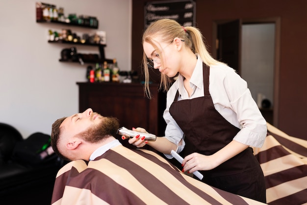 Free photo woman shaving her client's mustache at the barber shop