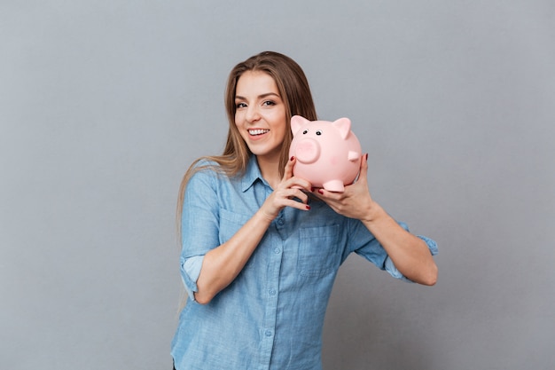 Woman in shirt holding moneybox in hands