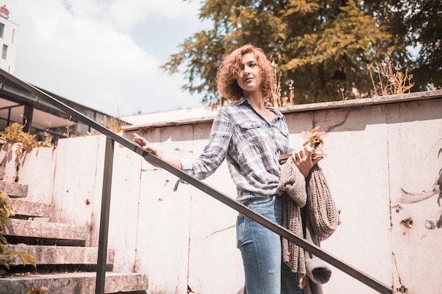 Free photo woman in shirt and jeans going down on steps