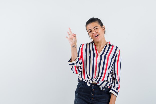 woman in shirt, skirt showing ok gesture and looking confident