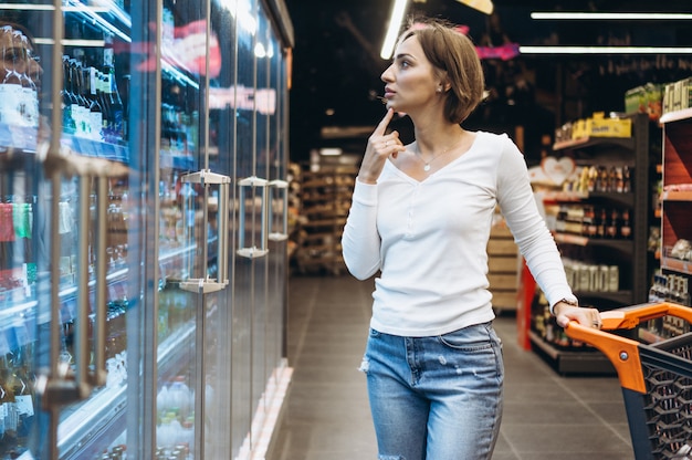 Woman shopping at the grocery store, by the refrigerator