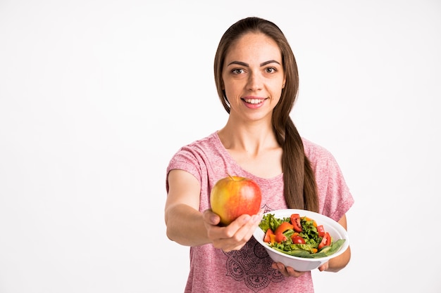 Woman showing an apple and holding a salad