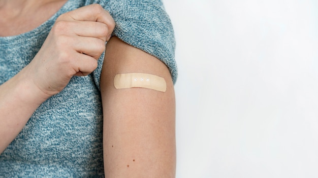 Free Photo woman showing bandage on arm after vaccine shot