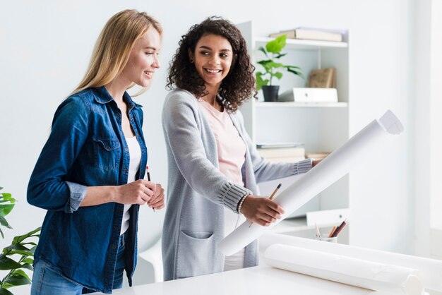 Woman showing blond female coworker paper sheet