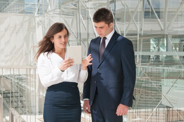 Woman showing man data on tablet, woman looking astonished