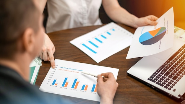 Woman showing a man finance diagrams on the table. Laptop, papers