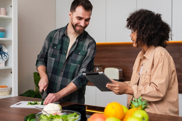 Free photo woman showing something on tablet to man cooking