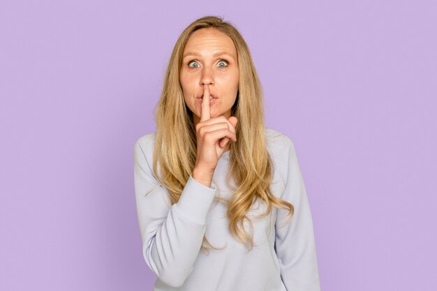 Woman shushing gesture on purple background