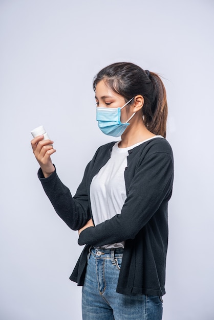 A woman sick standing with a bottle of medicine