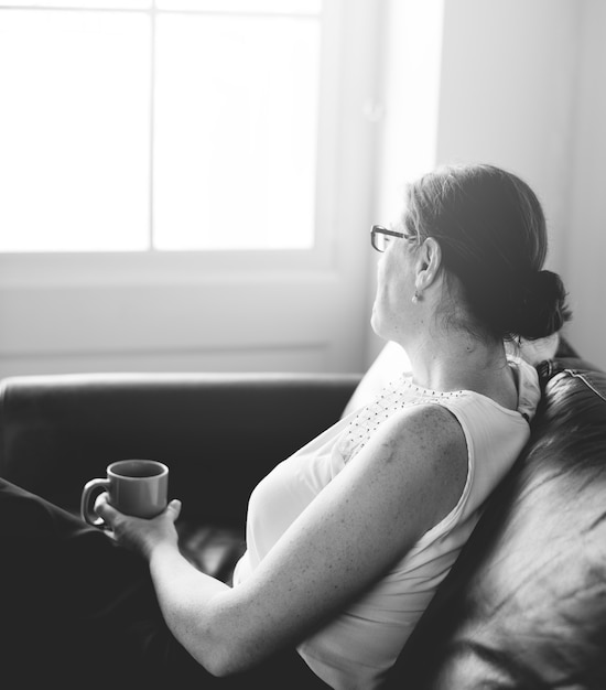 Free photo woman sipping a drink sitting on a counch