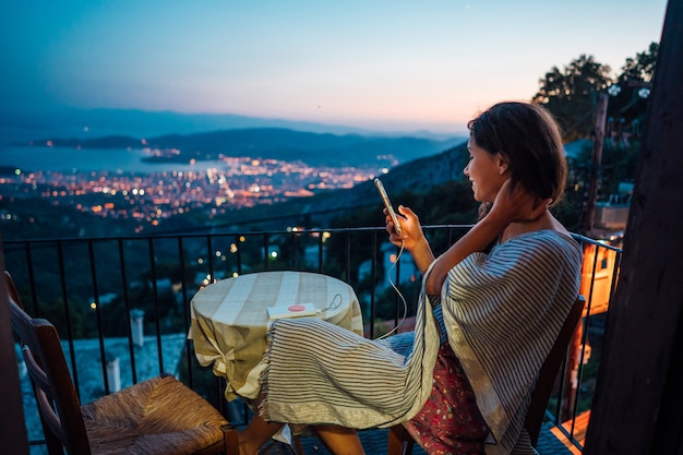 Woman sits on the balcony, in the background the night city