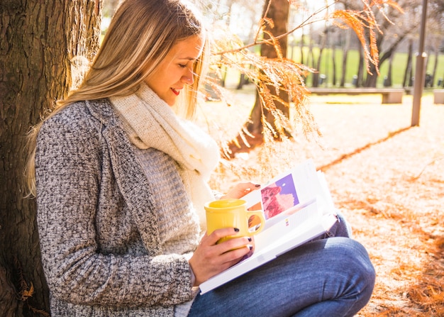 Free Photo woman sitting in autumn park and reading