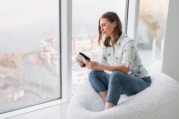 Free photo woman sitting on a bean bag  with her phone