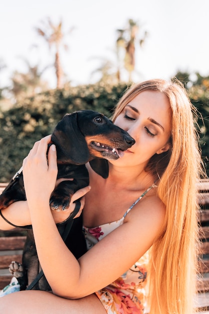 Free Photo woman sitting on bench with her dog