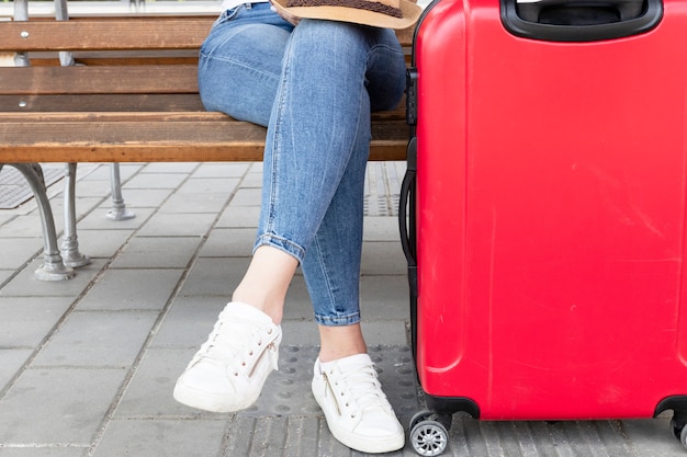 Free photo woman sitting on a bench with luggage