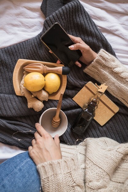 Woman sitting on blanket with mobile phone and making juice